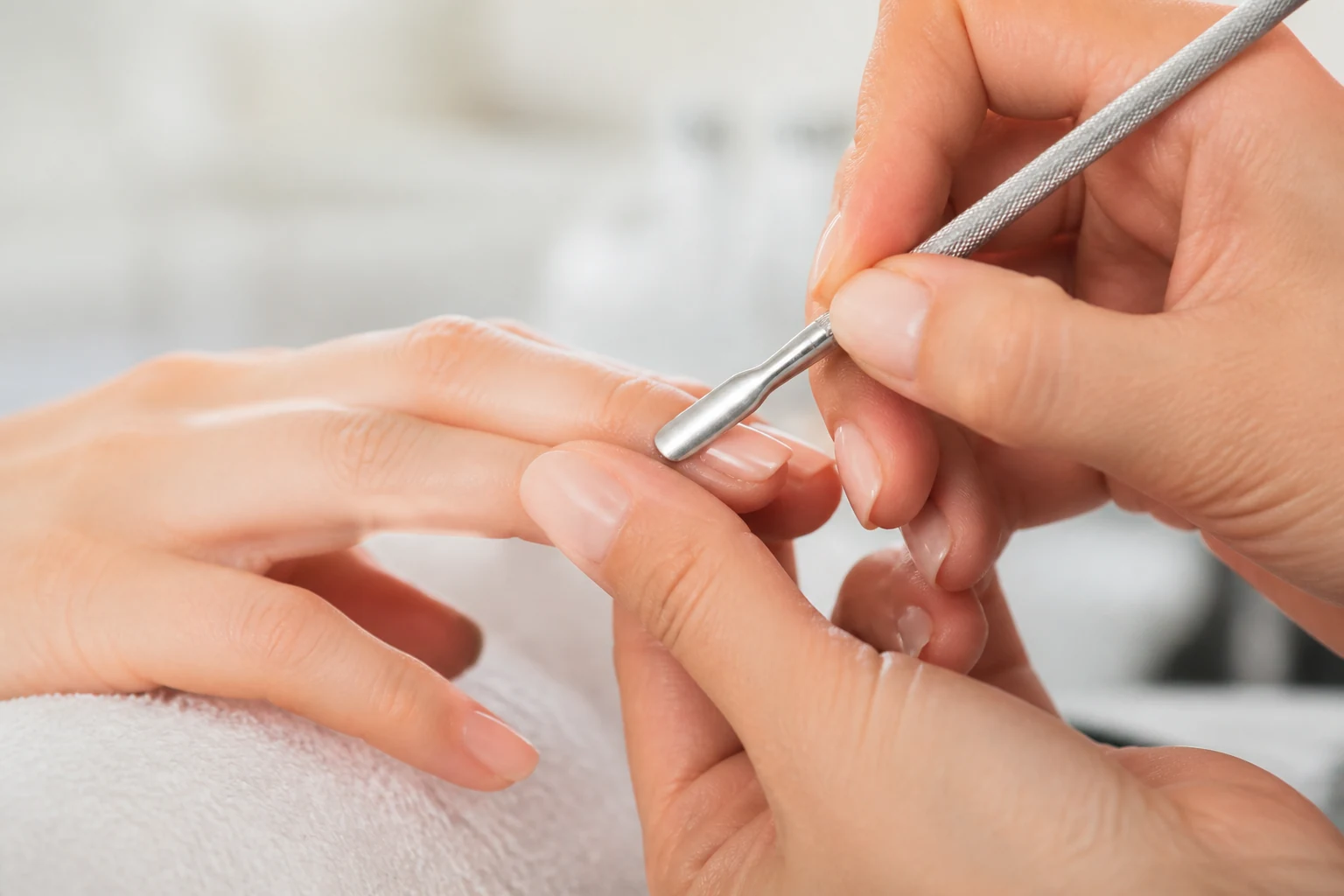 Gros plan sur des cuticules et la base de l'ongle lors d'un soin des mains