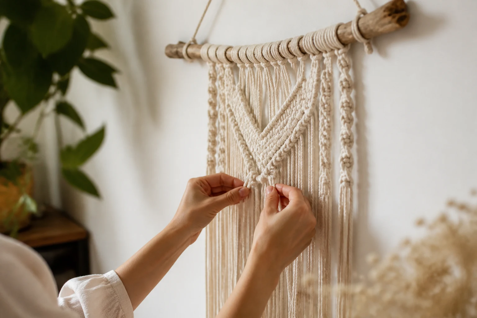 Suspension murale en macramé écru nouée à la main sur une branche de bois