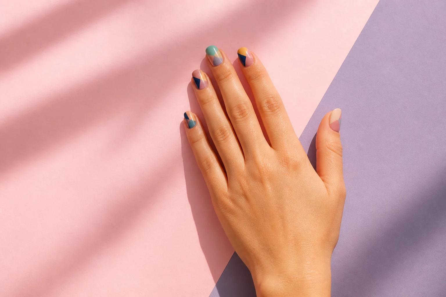 Mains présentant un nail art coloré avec motifs décoratifs sur les ongles