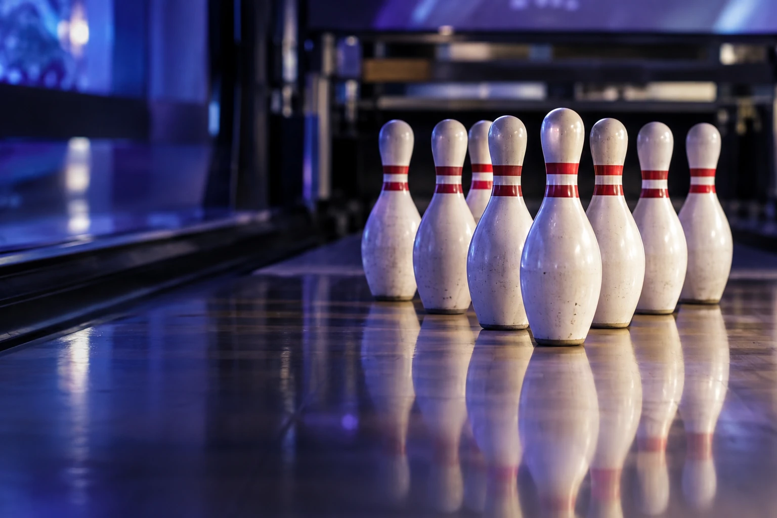 Neuf quilles de bowling alignées en triangle sur une piste brillante