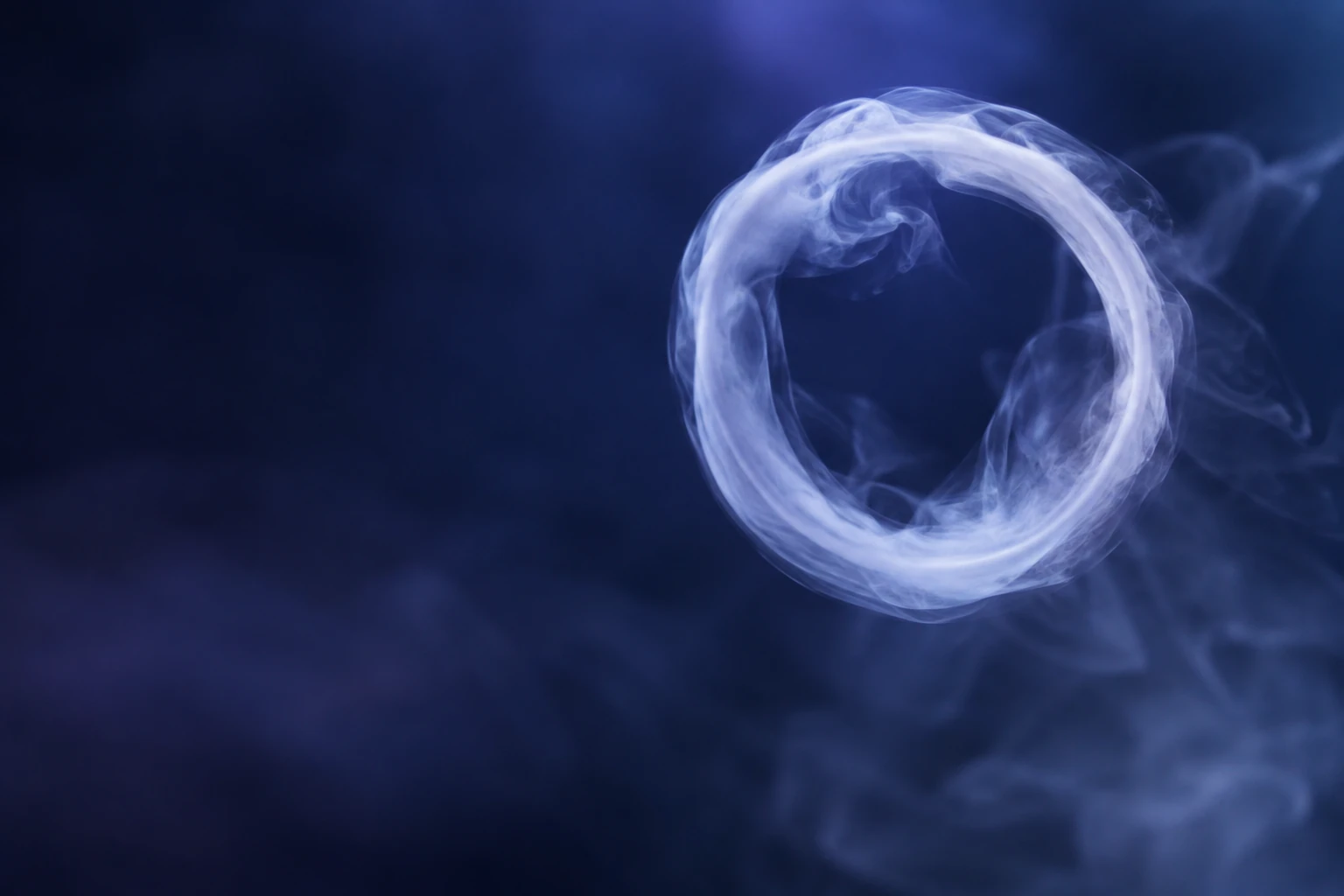 Anneau parfait de fumée ou bulle de savon ronde flottant dans un fond indigo