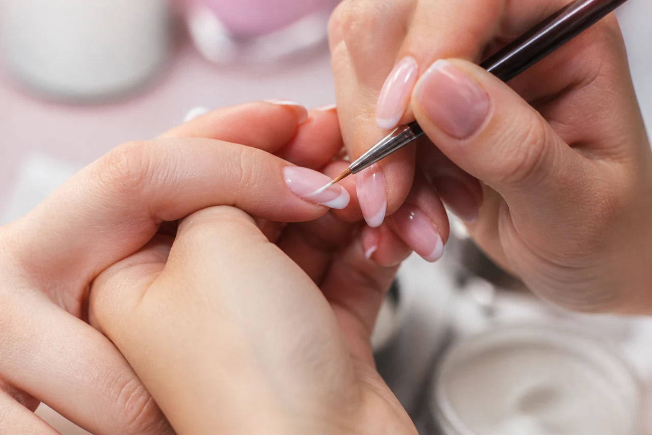 Gros plan sur des ongles avec le fin sourire blanc de la manucure française