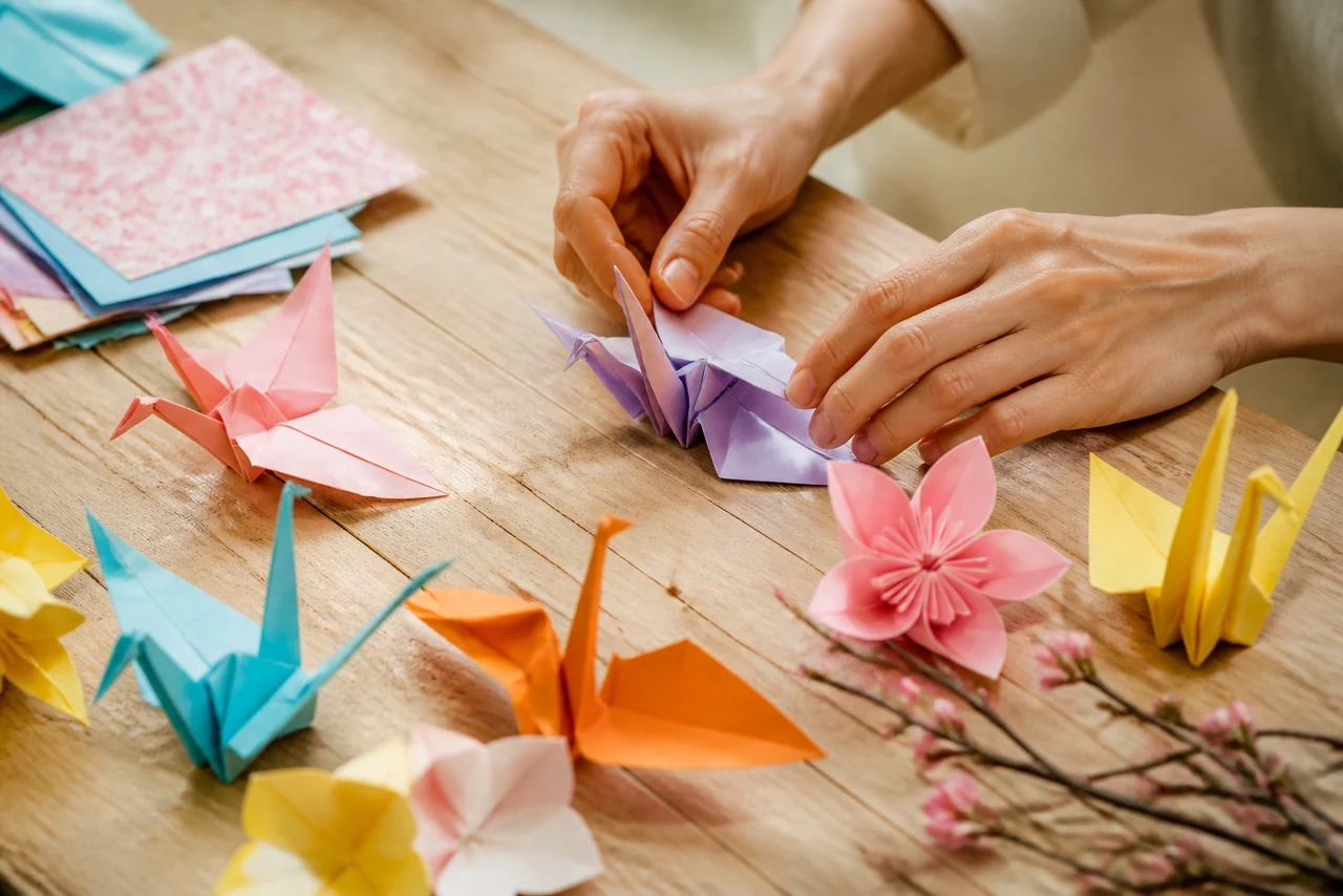 Mains pliant une feuille de papier selon les techniques de base de l’origami