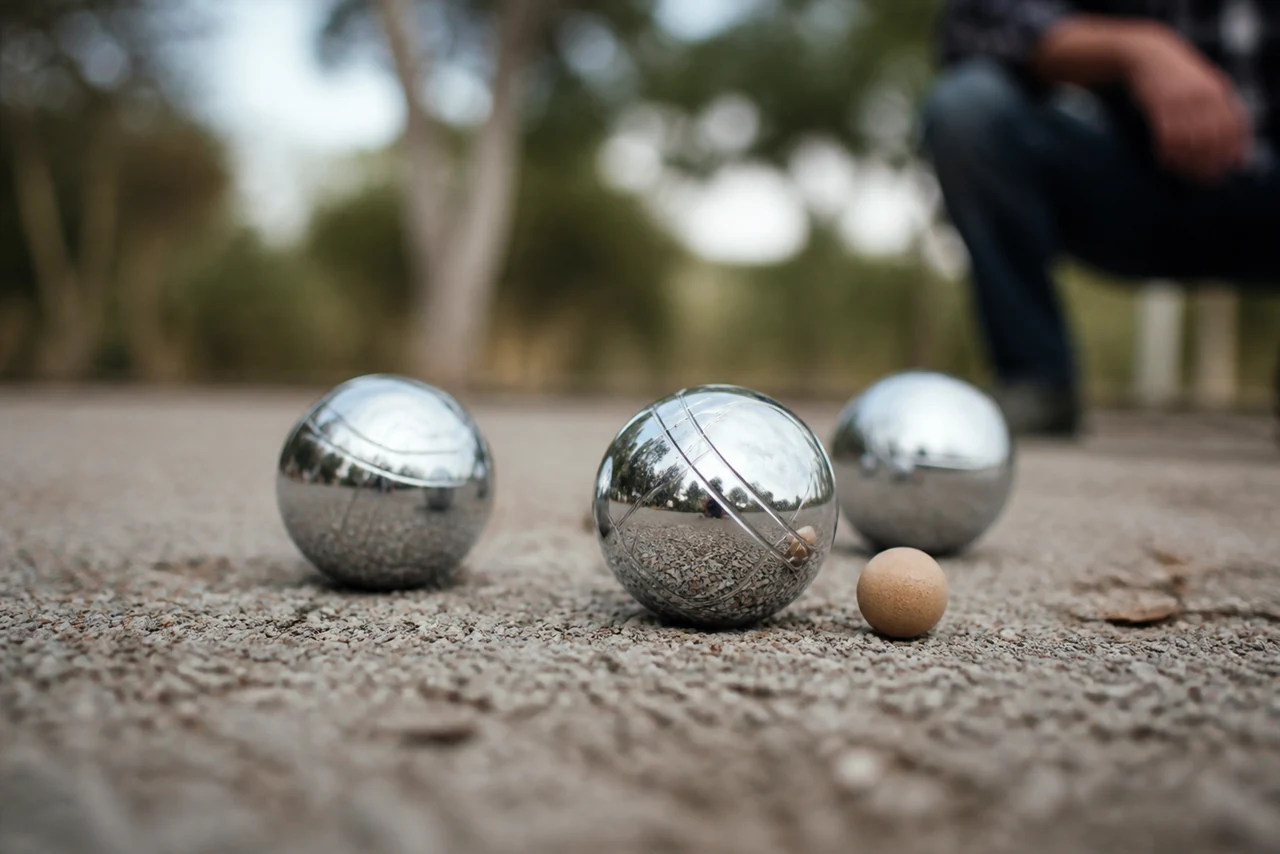 Boules de pétanque métalliques posées près du cochonnet sur un terrain gravillonné
