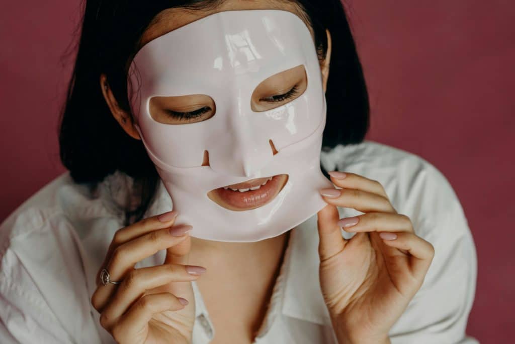 Asian woman applying a face mask as part of her skincare routine, promoting beauty and self-care.